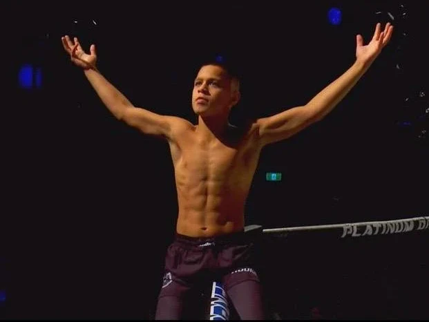 Mikail Tamoz raising his arms confidently inside the MMA ring