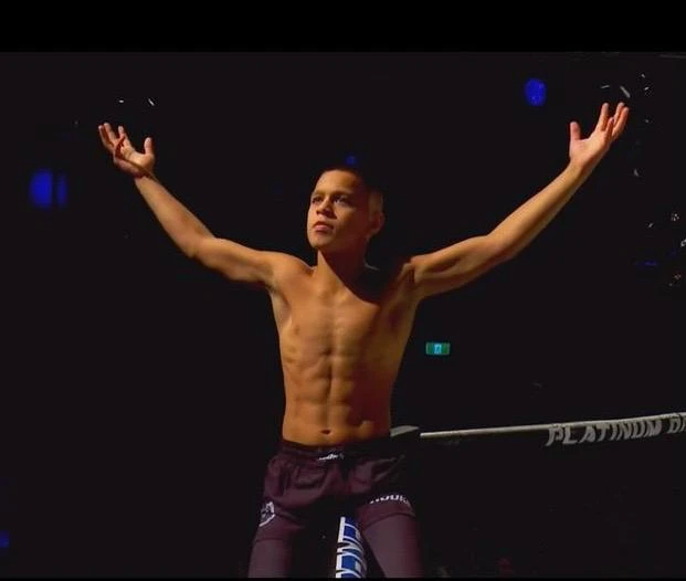 Mikail Tamoz raising his arms confidently inside the MMA ring