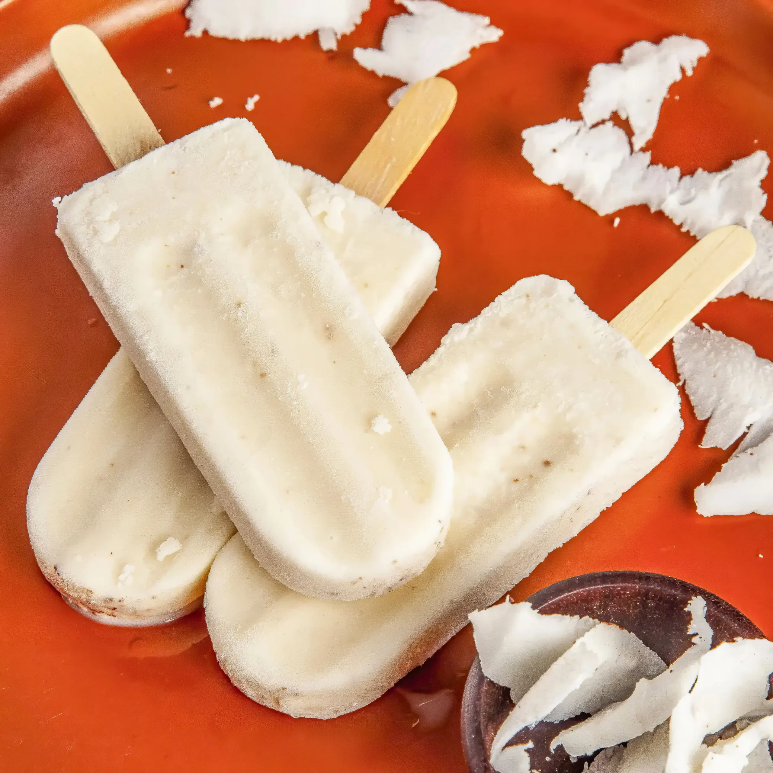 Creamy grass fed whey protein icy poles made with coconut milk on an orange plate