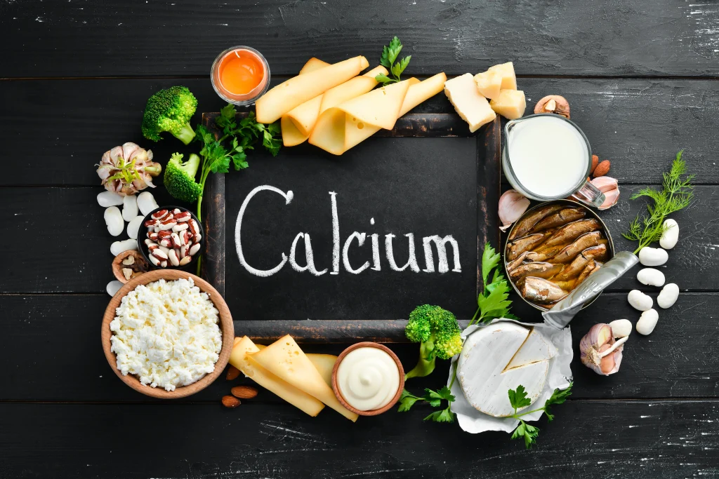 products-containing-natural-calcium-cheese-milk-parmesan-sour-cream-fish-almonds-parsley-garlic-broccoli-black-wooden-background-top-view-free-copy-space